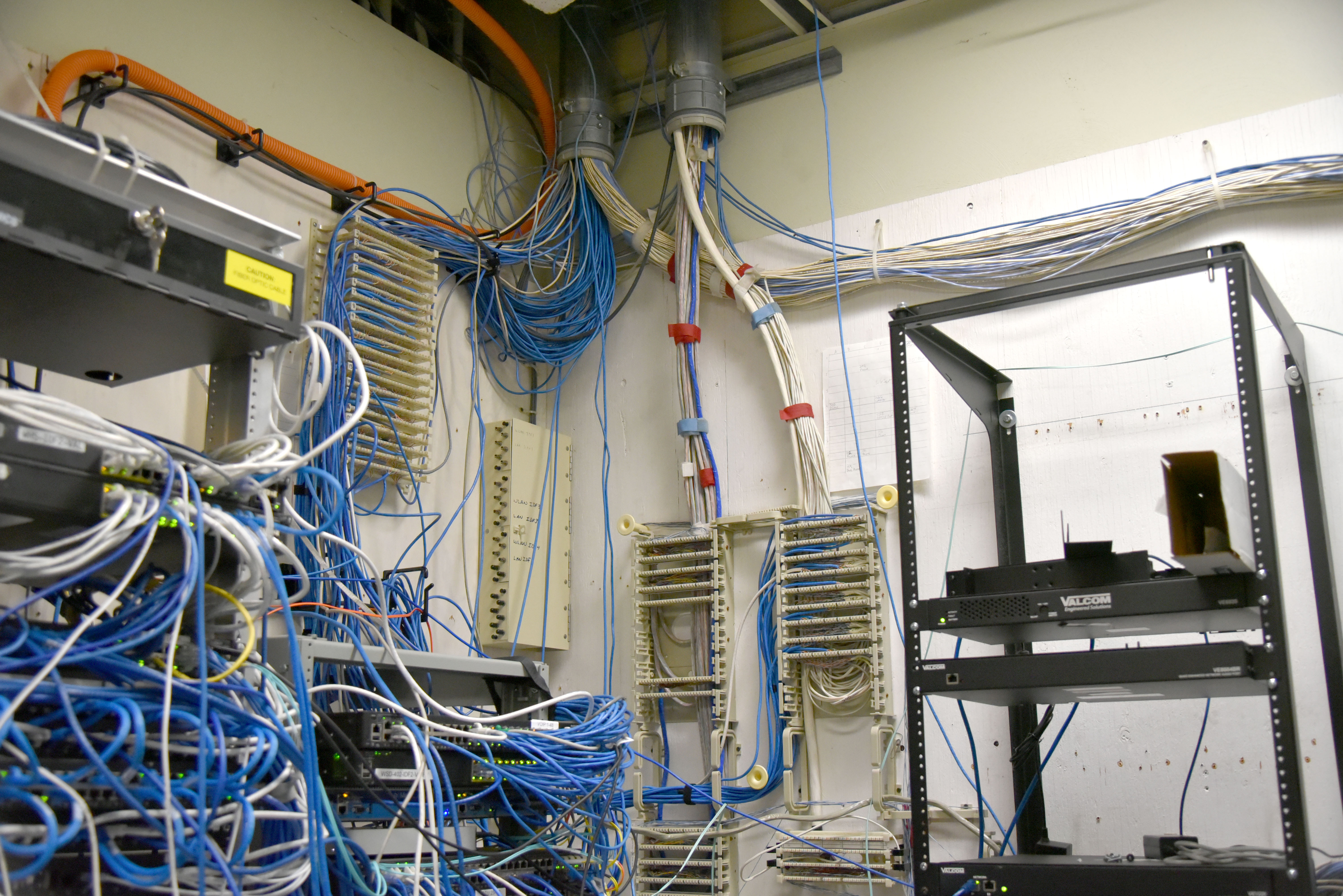 A WHS network room with a chaotic tangle of ethernet and data cables hanging from racks and the ceiling, the result of decades of ad-hoc technology upgrades