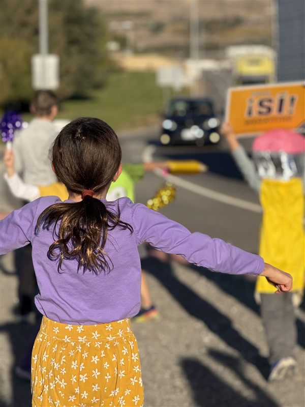 Kids waving Yes for Wenatchee Schools signs at a busy Wenatchee intersection